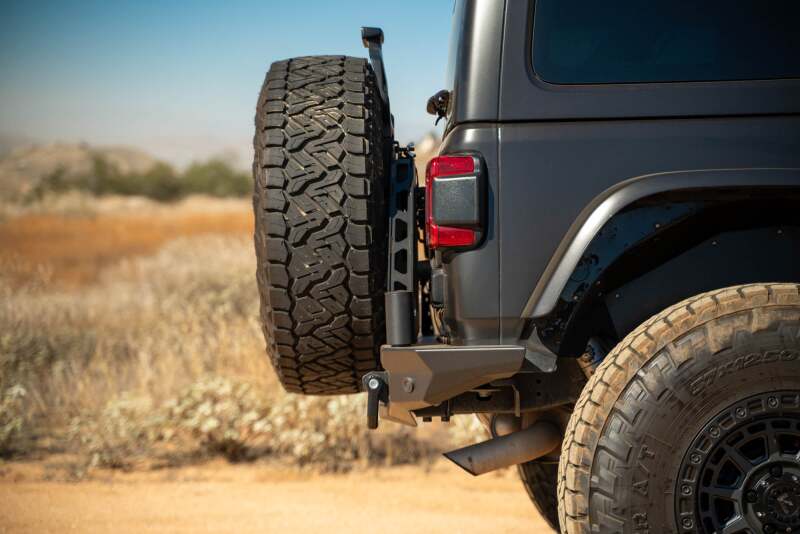 DV8 Offroad Jeep Wrangler JL MTO Series bumper spare tire swing gate tailgate accessory, mounted on rear of vehicle.