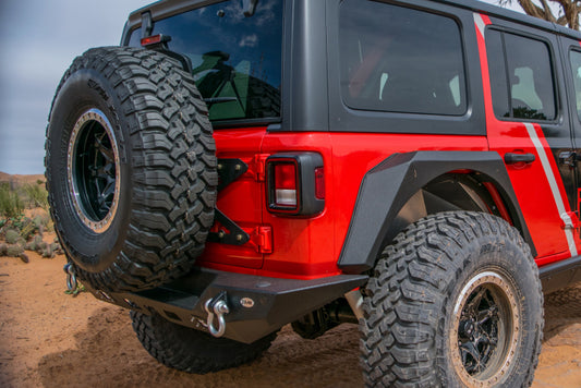 DV8 Offroad Jeep Wrangler JL tailgate-mounted tire carrier on chase rack, securely holding a spare tire on a 2018+ Jeep Wrangler JL.