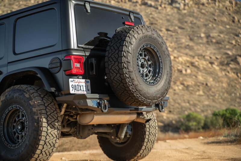 DV8 Offroad Jeep Wrangler JL MTO Series bumper spare tire swing gate tailgate accessory, showing mounted spare tire and swing arm.