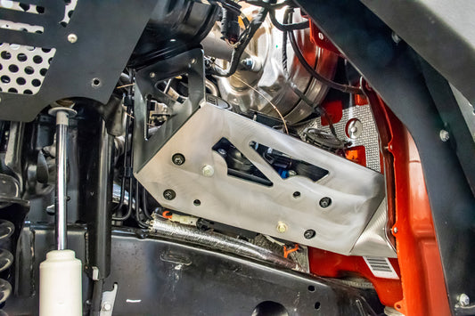 DV8 Offroad Jeep JL/JT engine bay compressor mount for air suspension, showing the black metal bracket installed in the engine compartment.