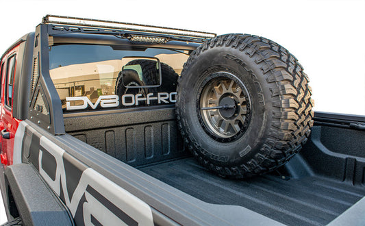 DV8 Offroad Jeep Gladiator universal in-bed tire carrier mounted on chase rack, showcasing rugged off-road vehicle accessories