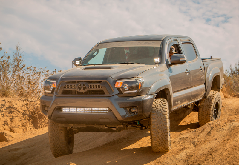 Cali Raised LED Toyota Tacoma ditch light brackets kit with blue backlit can pods, designed for 05-15 model trucks.