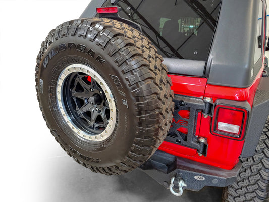 DV8 Offroad Chase Racks tire carrier for 2018+ Jeep Wrangler, sturdy metal mount with secure tire attachment.
