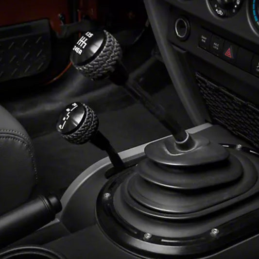 Black DV8 Offroad 2011-2018 Jeep JK 6-speed shift knob showing textured surface and ergonomic design inside a vehicle interior.