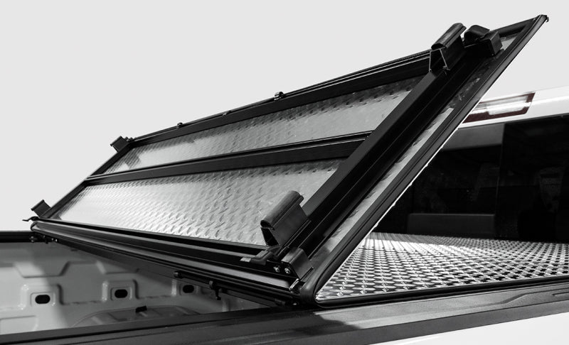 Access LOMAX tri-fold truck bed cover in black diamond mist on a 2019 Dodge Ram 1500 with 5ft 7in box, exterior truck bed accessory.