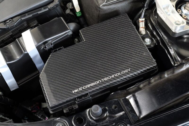 HKS dry carbon fuse box cover for FL5, lightweight carbon accessory with a sleek black finish, designed for car engine bay protection.