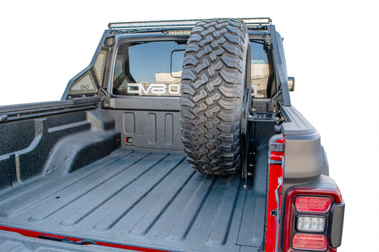 DV8 Offroad Jeep Gladiator 2019+ universal in-bed tire carrier mounted on chase rack, showing rugged off-road design and installation.