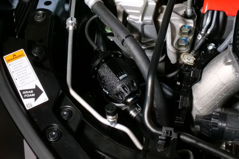 HKS Super SQV4 FL5 Black Edition blow off valve installed on a vehicle, showcasing its sleek black finish and compact design.