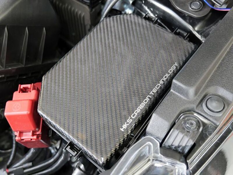 HKS 2023 Toyota GR Corolla dry carbon engine bay fuse box cover showing sleek carbon fiber finish and precise fit.