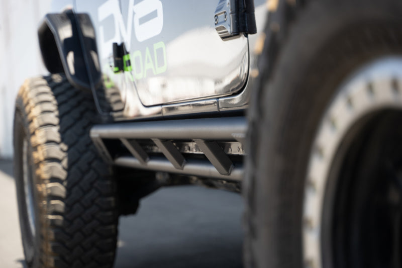 DV8 Offroad 18-23 Jeep Wrangler JL 4-door FS-15 Series rock sliders mounted on the vehicle's side for protection and durability