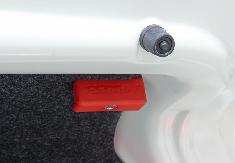 Red Perrin Performance trunk handle for Subaru BRZ, Toyota GR86, and FR-S hatchbacks, mounted on the vehicle's trunk.