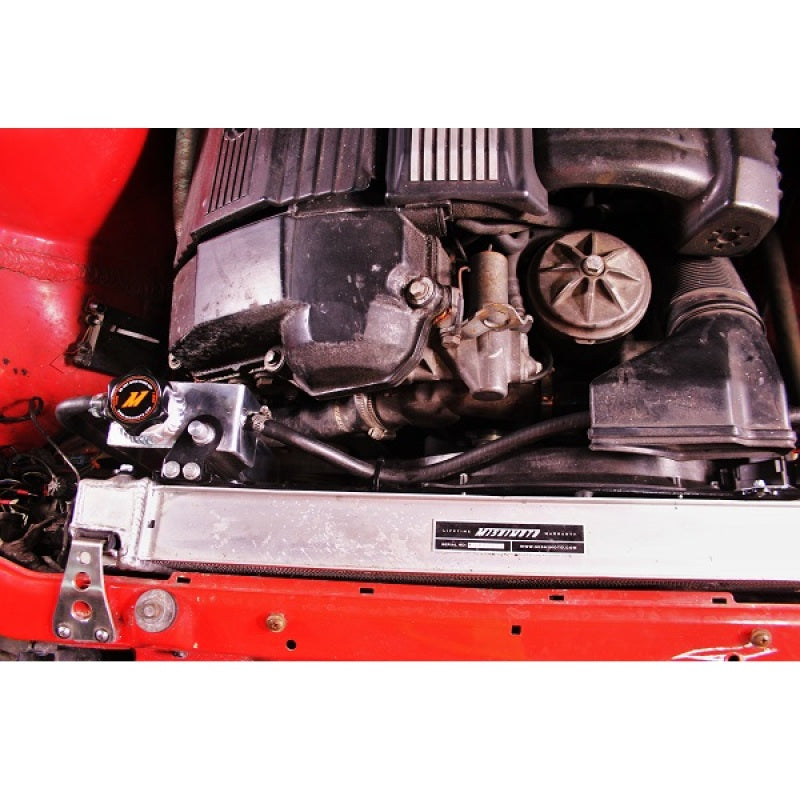 Mishimoto coolant expansion tank for BMW 3 Series E36, aluminum reservoir with attached hoses and mounting point.