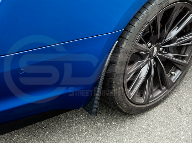 Pair of black carbon fiber mud flaps for 2022-up Cadillac CT5-V Blackwing by Street Driven Performance, mounted on front and rear wheels.