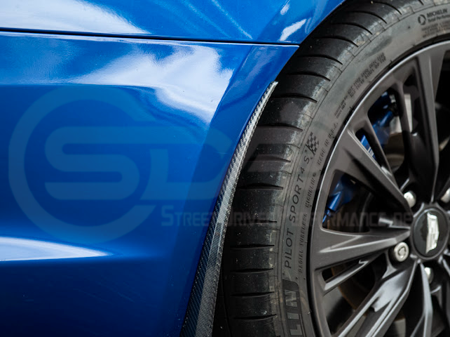 Pair of black carbon fiber mud flaps for 2022-up Cadillac CT5-V Blackwing by Street Driven Performance, installed on front and rear wheels.