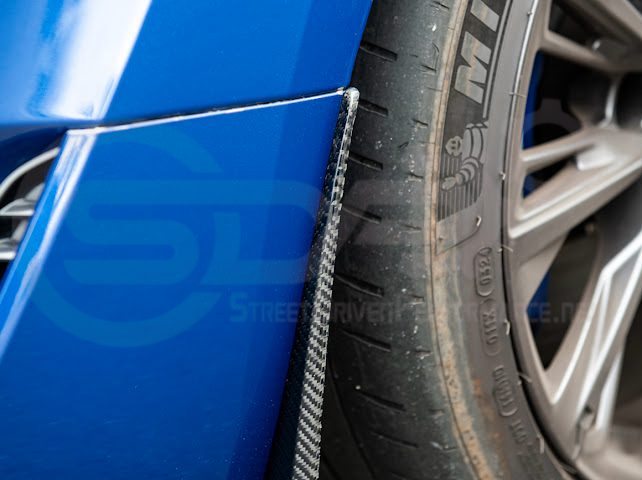 Pair of carbon fiber front and rear mud flaps for Cadillac CT5-V Blackwing, by Street Driven Performance, with black finish and textured surface.