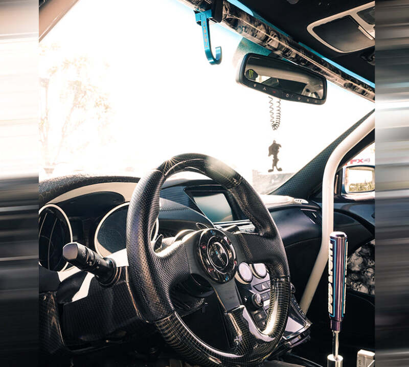 NRG CNC aluminum steering wheel hook with red finish and laser logo attached to a steering wheel for easy hanging.