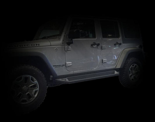 Matte black DV8 Offroad steel rock slider side steps for 2007-2018 Jeep Wrangler JK four-door model, designed for off-road protection.