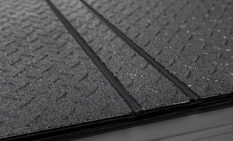 Access LOMAX Pro Series tri-fold hard tonneau cover in black diamond mist for Chevy/GMC 1500 6ft 6in bed, sturdy and secure.