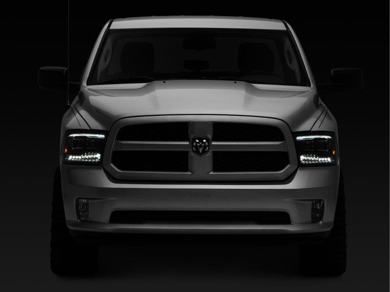 Raxiom LED projector headlights for 2009-2018 RAM 1500 with black housing, clear lens, switchback turn signals, and modern design.