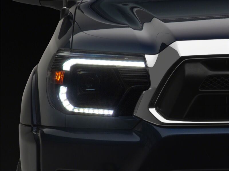 Raxiom black housing projector headlights with clear lenses for Toyota Tacoma 2012-2015, featuring switchback LED turn signals.