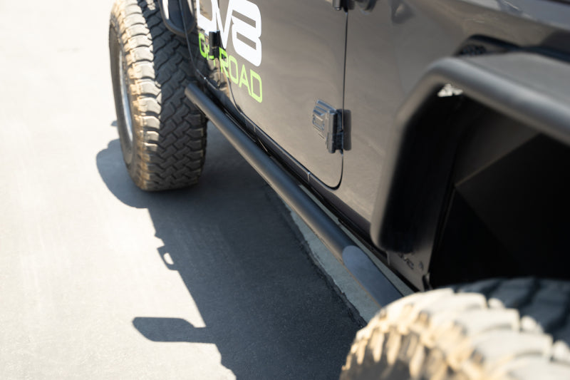 DV8 Offroad 18-23 Jeep Wrangler JL 4-door FS-15 rock sliders mounted on side of black Jeep, exterior body armor for off-road protection