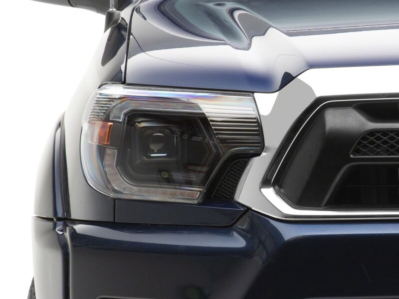 Raxiom black housing projector headlights with clear lens for 2012-2015 Toyota Tacoma, featuring switchback LED turn signals.