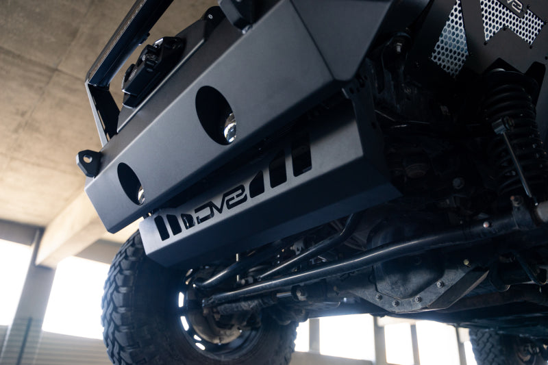 DV8 Offroad Jeep Wrangler JL/JT front bumper sway-bar disconnect motor skid plate mounted on vehicle underside.