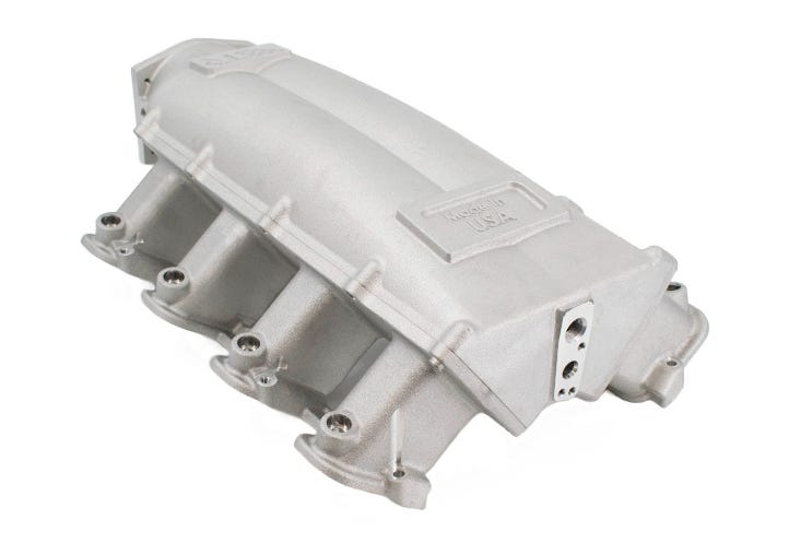 BTR Trinity Intake Manifold for cathedral port engines, natural finish, shown on engine component in close-up image