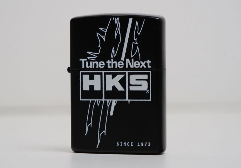 HKS Zippo lighter TTN with sleek design and branding, featuring a classic metal case and open lid displaying the ignition mechanism.