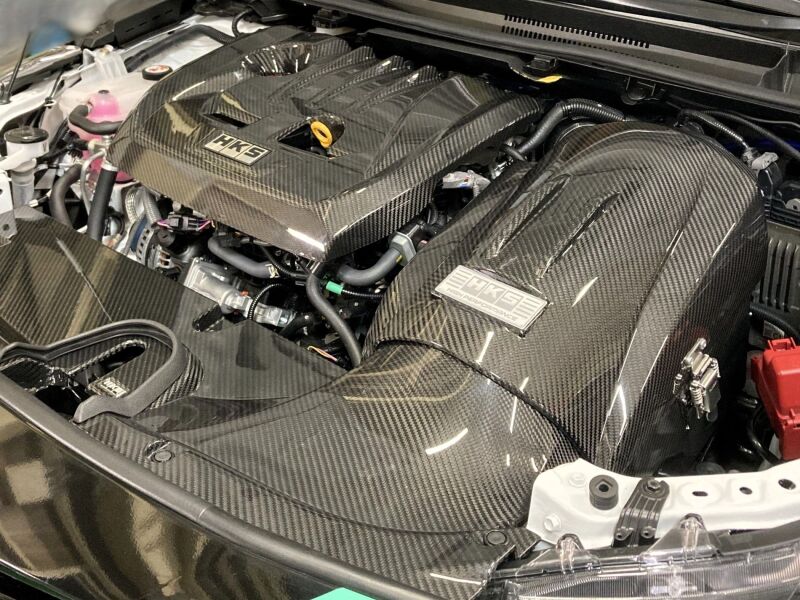 HKS Cold Air Intake Full Kit GZEA14H installed in a vehicle, showing the sleek intake pipe and air filter for improved engine airflow.