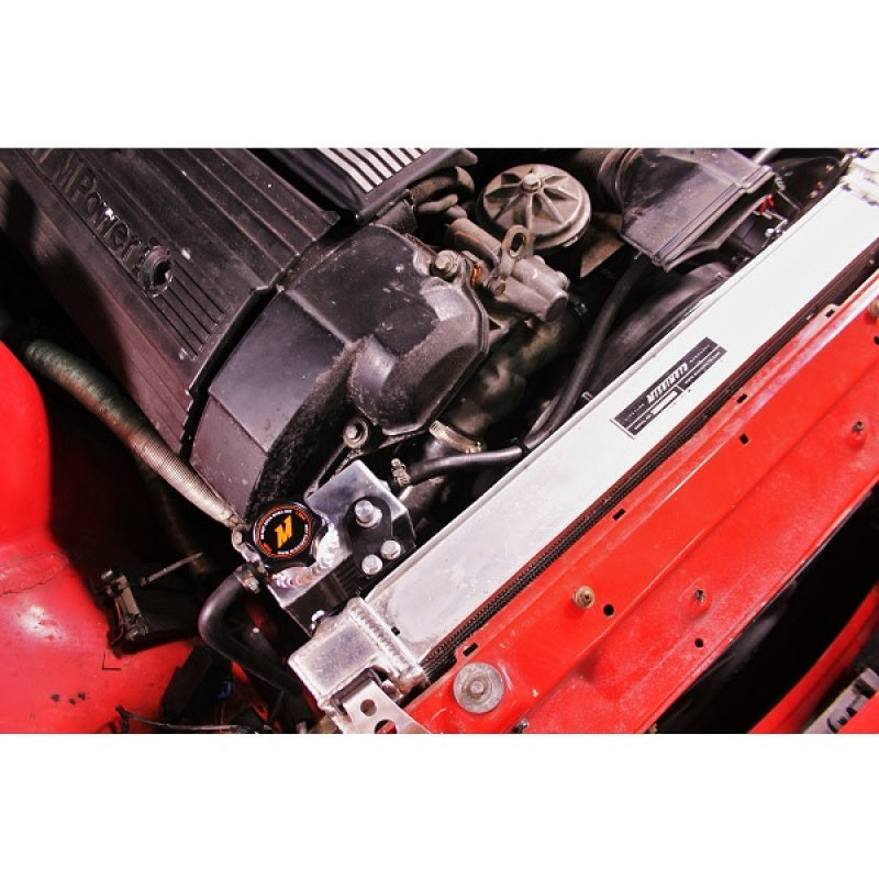 Mishimoto aluminum coolant expansion tank for BMW 3 Series 92-99, close-up view showing sleek silver reservoir with mounting features.