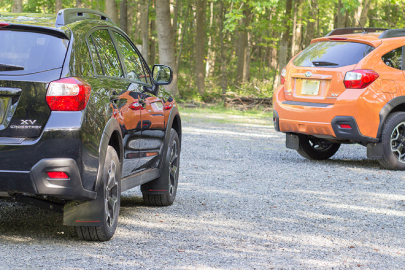 Black mud flaps with orange Rally Armor logo on a 2013-2017 Subaru Crosstrek XV, designed for protection and style.