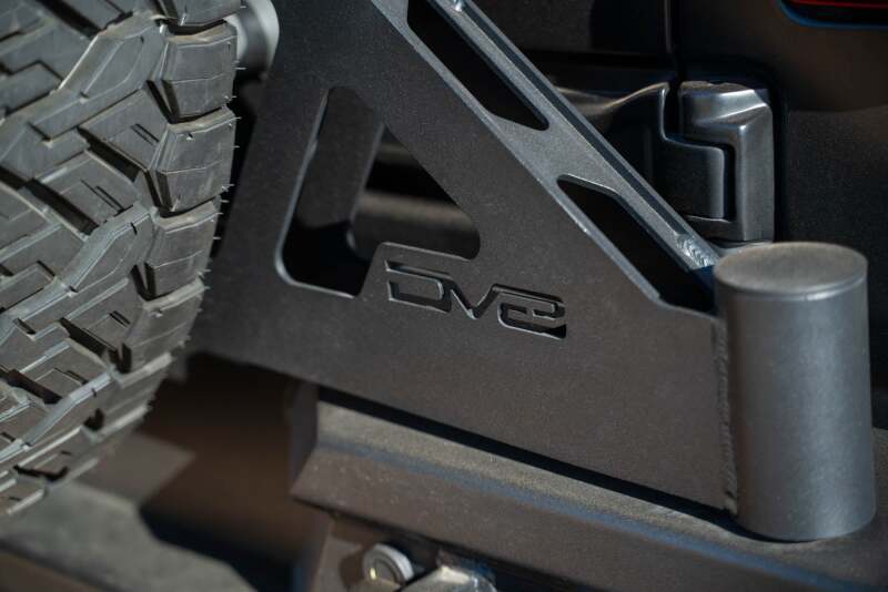 DV8 Offroad Jeep Wrangler JL MTO Series bumper spare tire swing gate tailgate accessory showing mounted tire and rugged bumper.