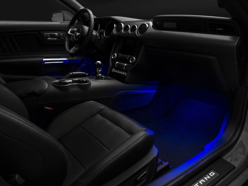 Raxiom blue LED footwell lighting kit installed inside a 2015-2023 Ford Mustang interior, illuminating the footwell area.
